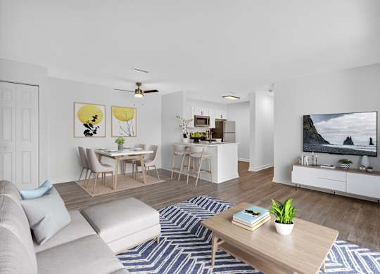 A living room with a grey sofa, a wooden coffee table, a TV, and a painting on the wall.