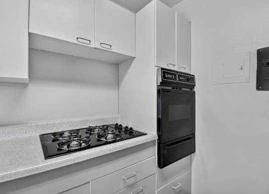 A black and white photo of a kitchen with a stove and oven.
