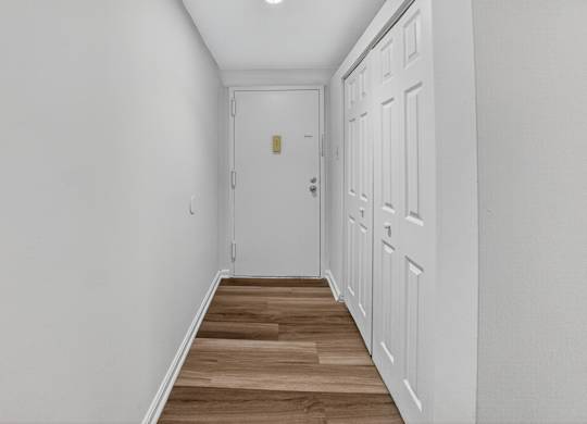 A hallway with a white door and a wooden floor.
