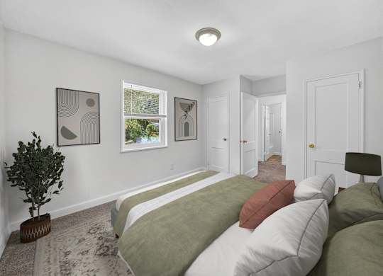 A bedroom with a bed, pillows, and pictures on the wall.