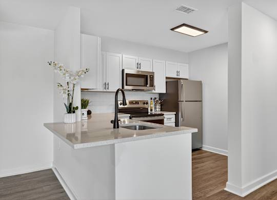 A kitchen with white cabinets and a stainless steel refrigerator.