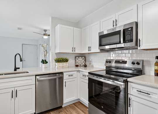 A modern kitchen with white cabinets and stainless steel appliances.