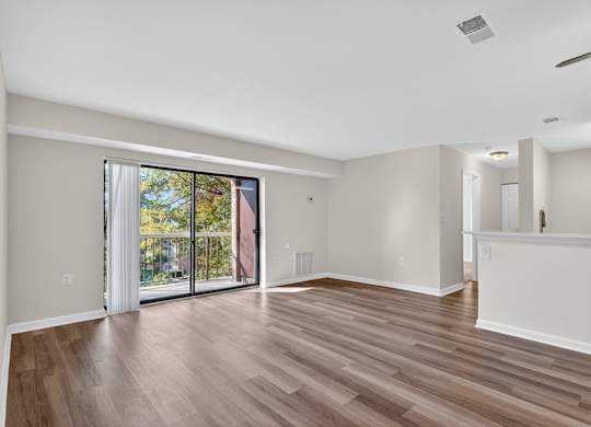 A room with wooden flooring and sliding glass doors.