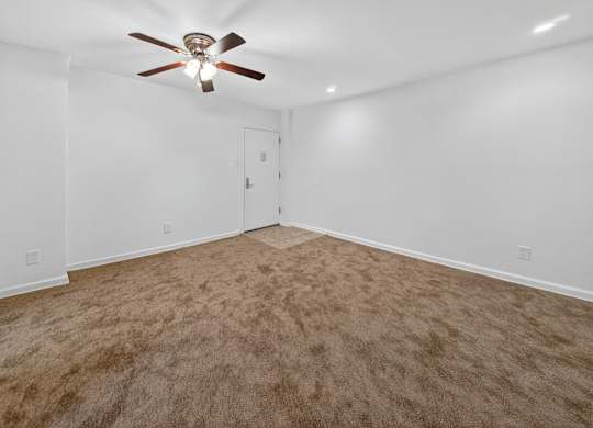 A room with a ceiling fan and carpeted floor.
