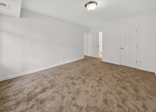 A room with a carpeted floor and two doors.