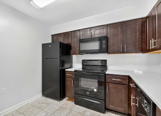 A kitchen with black appliances and brown cabinets.