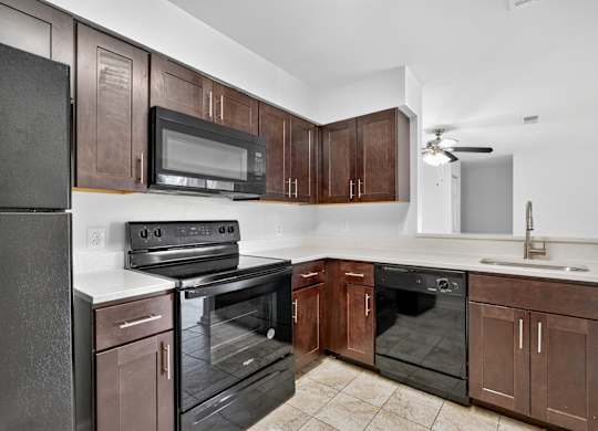 A kitchen with brown cabinets and black appliances.