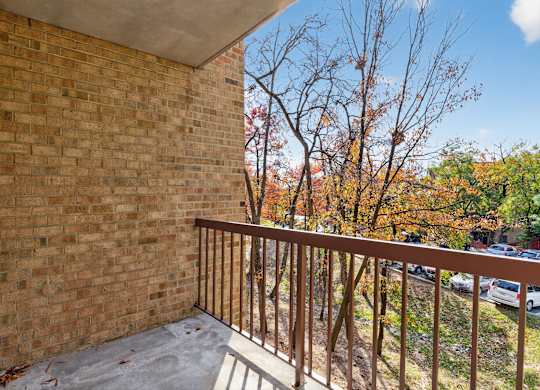 A balcony with a brick wall and a metal railing.
