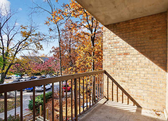 A balcony with a metal railing and a brick wall.