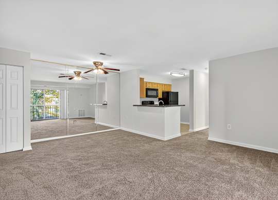 A spacious living room with a ceiling fan and a bar area.