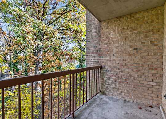 A balcony with a brick wall and a metal railing.