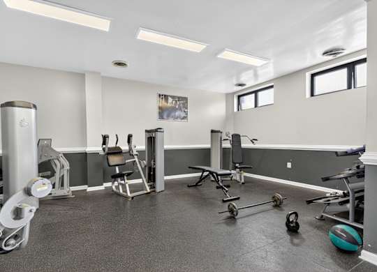A gym with a variety of equipment including weights and a bench.