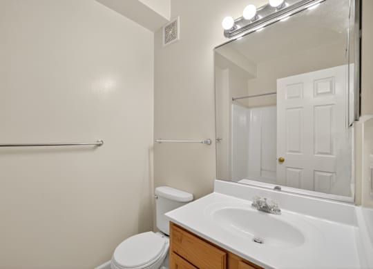 A white bathroom with a toilet, sink, and mirror.