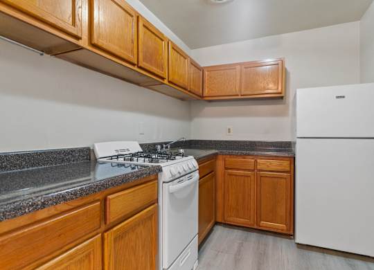 A kitchen with a white fridge, white stove and wooden cabinets.