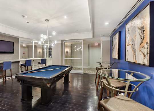 A room with a pool table and chairs.