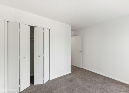 a bedroom with white walls and mirrored closet doors