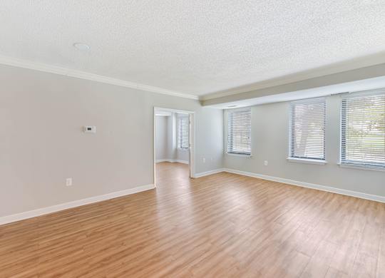 A room with wooden flooring and a window with blinds.