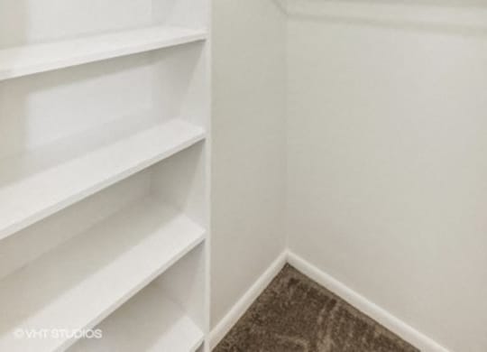 large closet with white shelves and a white wall and