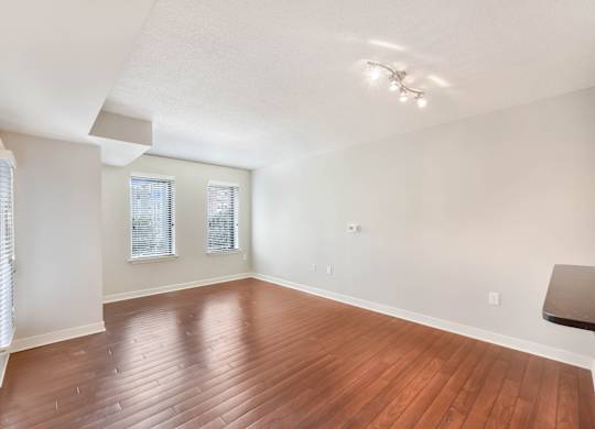 A room with wooden flooring and a window with blinds.