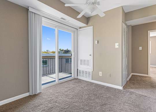 A room with a carpeted floor and a ceiling fan.