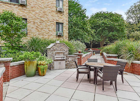 A patio with a table and chairs is surrounded by a brick wall and has a fireplace.