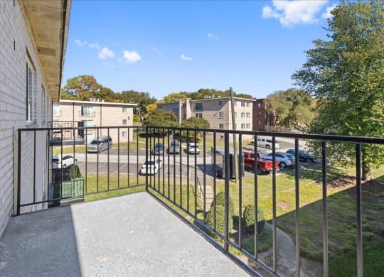 a balcony with a view of a parking lot and buildings