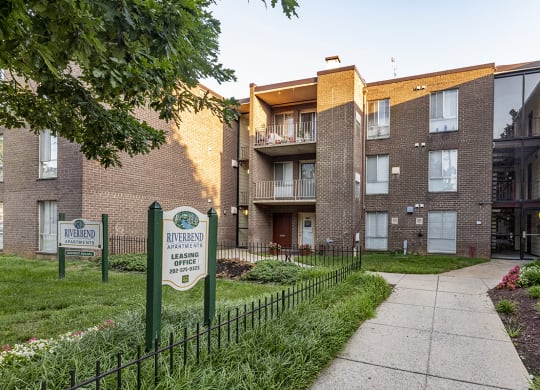 an apartment building with a sidewalk, fence and a sign in front