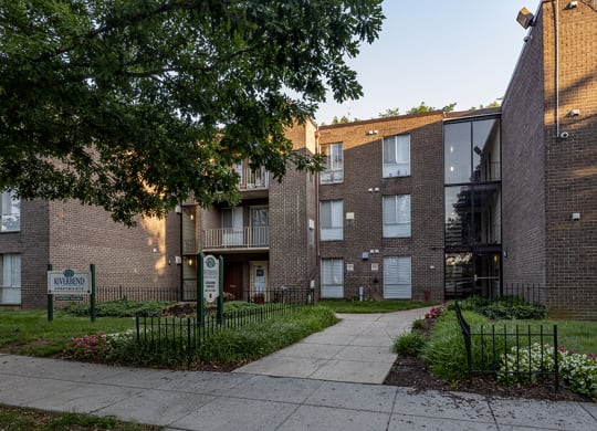 a brick apartment building with a sidewalk in front of it
