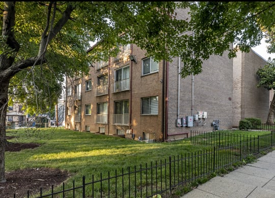 a brick building with a yard and a fence