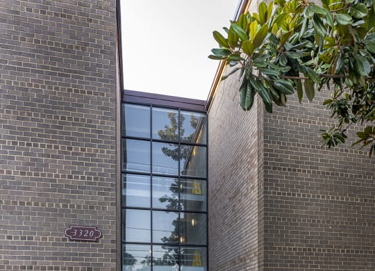 the front entrance of a brick building with a sidewalk and a glass door