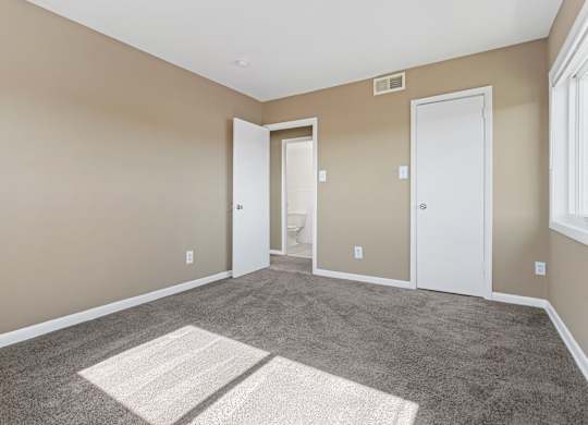 A room with a carpeted floor and two white doors.