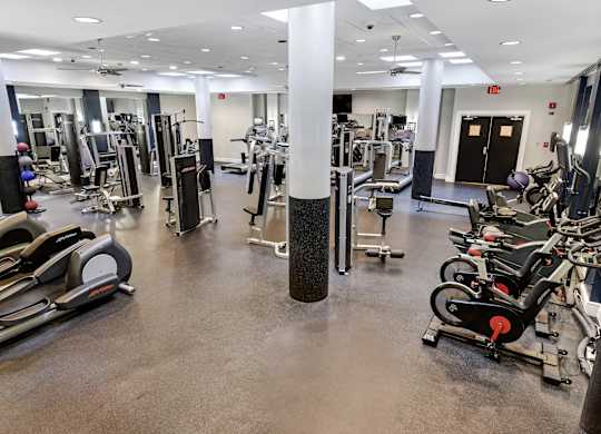 A gym with a variety of equipment including treadmills, weights, and exercise machines.
