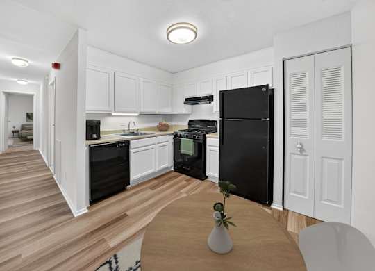 A kitchen with black appliances and white cabinets.