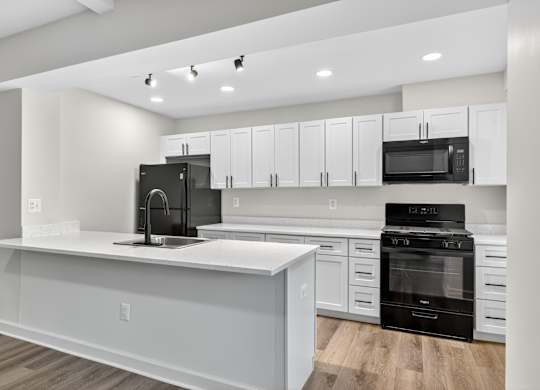 A modern kitchen with white cabinets and black appliances.