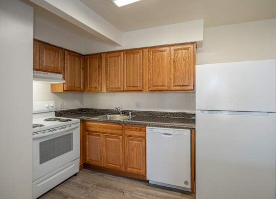 A kitchen with white appliances and wooden cabinets.