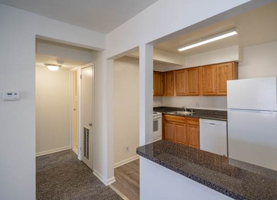A kitchen with white appliances and wooden cabinets.