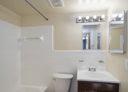 A white bathroom with a toilet, sink, and mirror.