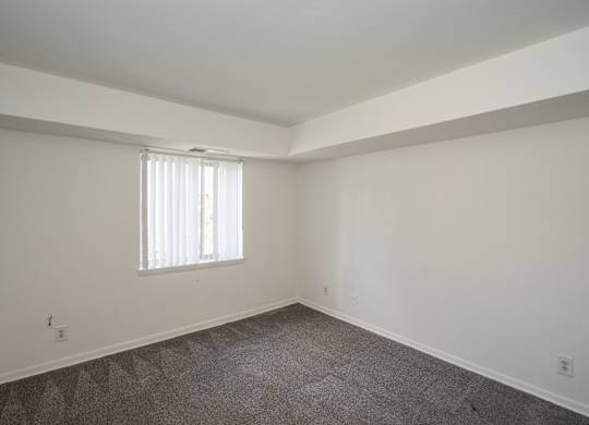 A room with a window and carpeted floor.