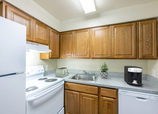 an empty kitchen with white appliances and wooden cabinets