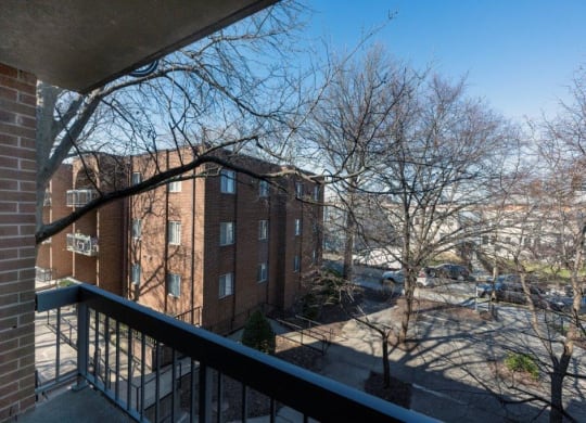a balcony with a view of a brick building and some trees