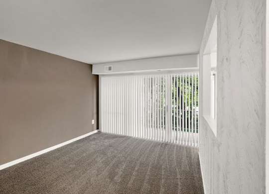 an empty living room with white blinds and a window