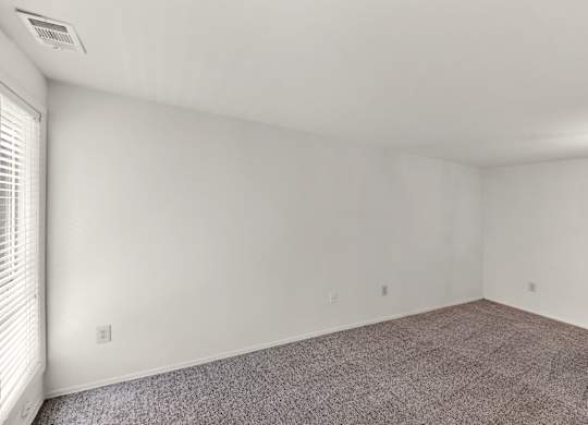 A room with white walls and a window with blinds.