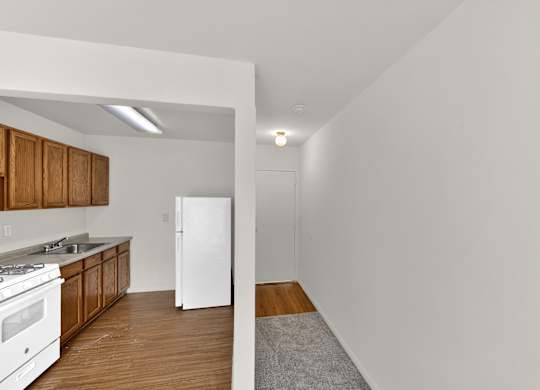 A kitchen with white appliances and wooden cabinets.