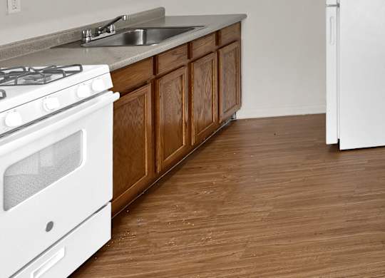 A kitchen with white appliances and wooden cabinets.