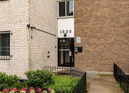 the front of a brick building with a sidewalk and grass