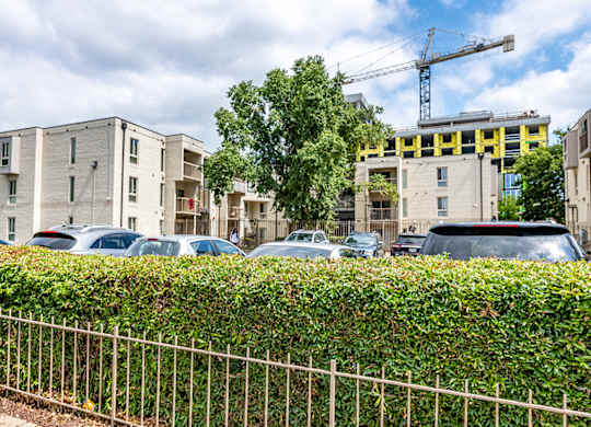 a parking lot in front of an apartment building with a crane