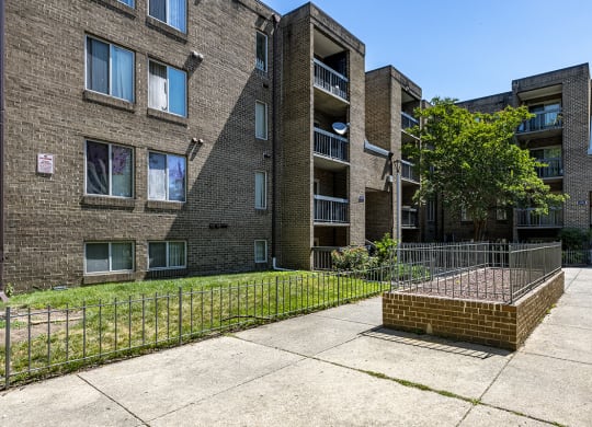 a brick apartment building with a yard and a fence