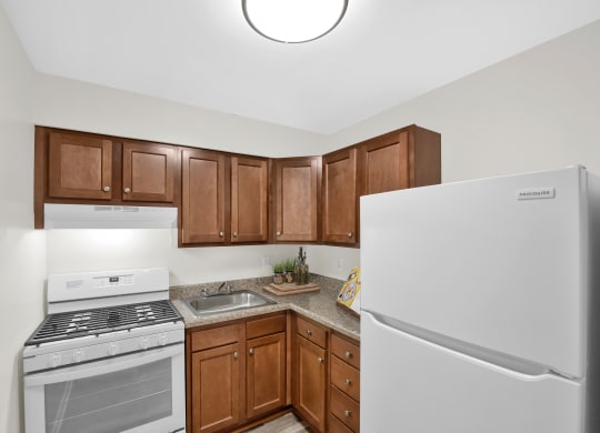 a kitchen with white appliances and brown cabinets and a refrigerator