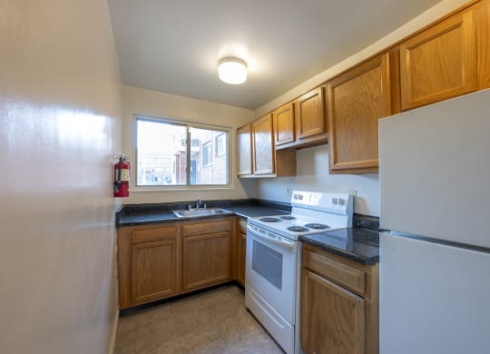 an empty kitchen with white appliances and wooden cabinets