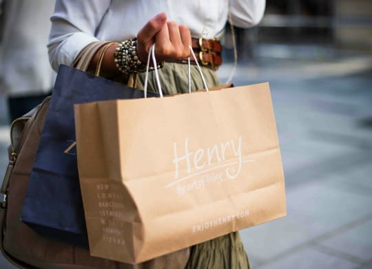a woman holding a paper bag with her shopping bags
